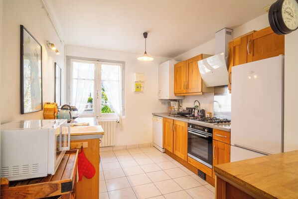 A modern kitchen with wooden cabinets, a built-in oven, a sink, and a stove. - 3 *** village house, bright veranda opening onto terrace and large garden (Quiberon)