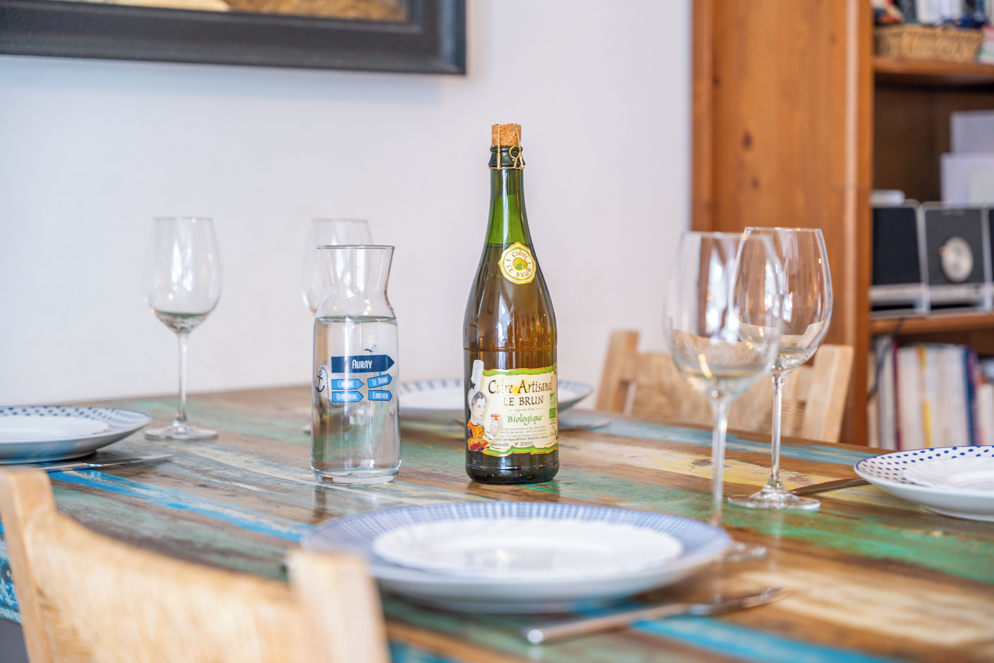 A dining table with a bottle of wine, glasses, and a water bottle.