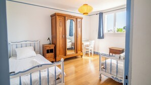 A bedroom with two beds, a wardrobe, a desk, and a window. - 3 *** village house, bright veranda opening onto terrace and large garden (Quiberon)