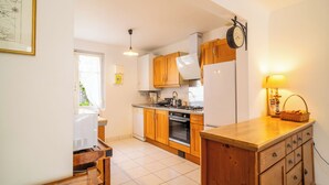 A kitchen with wooden cabinets, a stove, a refrigerator, and a clock on the wall. - 3 *** village house, bright veranda opening onto terrace and large garden (Quiberon)