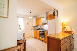 A kitchen with wooden cabinets, a stove, a refrigerator, and a clock on the wall. - 3 *** village house, bright veranda opening onto terrace and large garden (Quiberon)