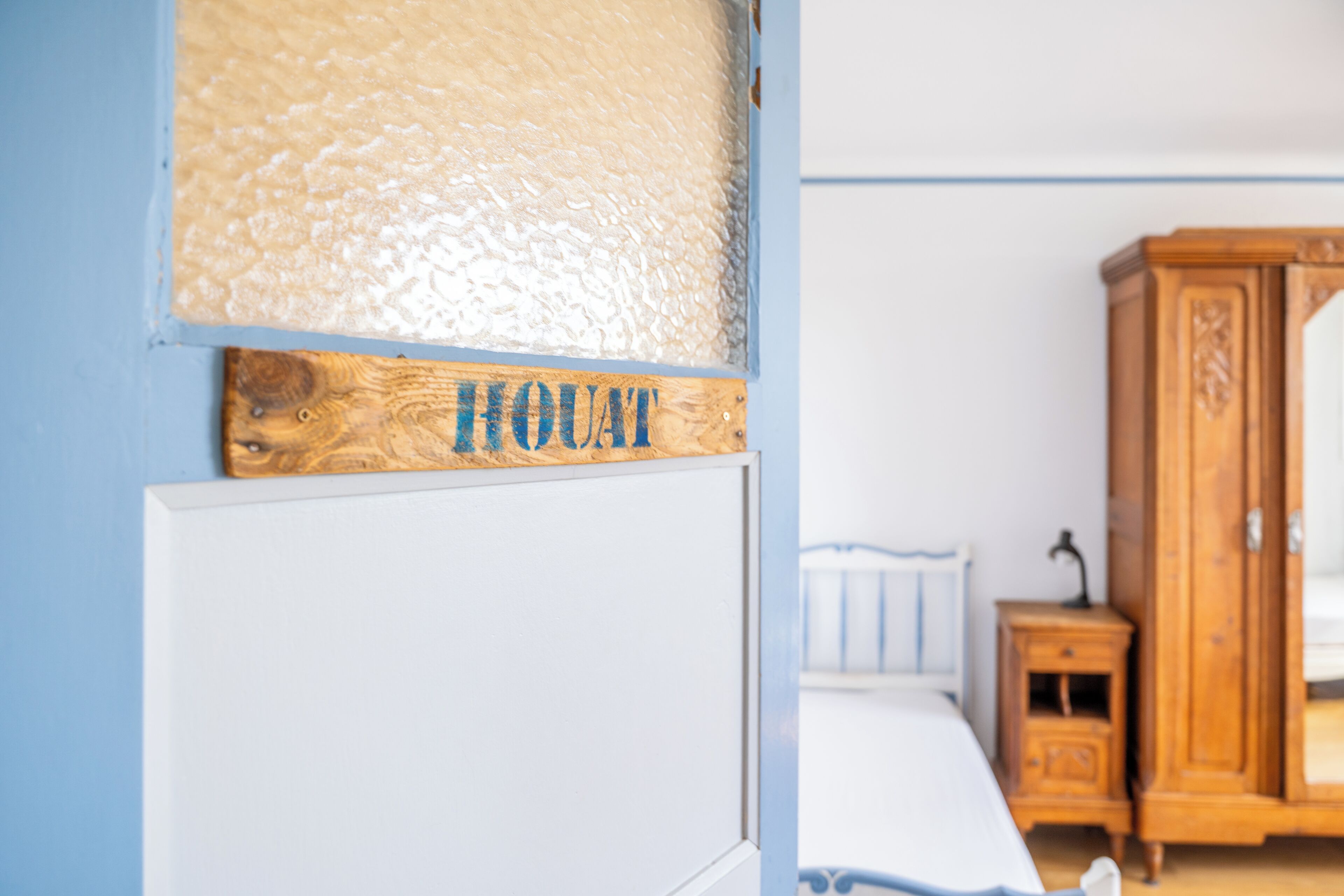 Une pièce comprenant un lit, une armoire en bois et un mur orné d’un panneau texturé et d’une enseigne en bois.