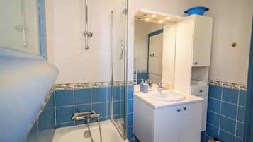 Une salle de bain avec une baignoire, une douche et un lavabo avec un miroir au-dessus.