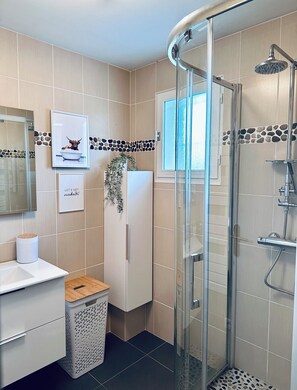 Bathroom features a curved glass shower enclosure, light-colored tiles, and a decorative stone border.