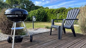 A wooden deck with a grill and a chair. - Charming Datcha in Normandy  (Les Damps)