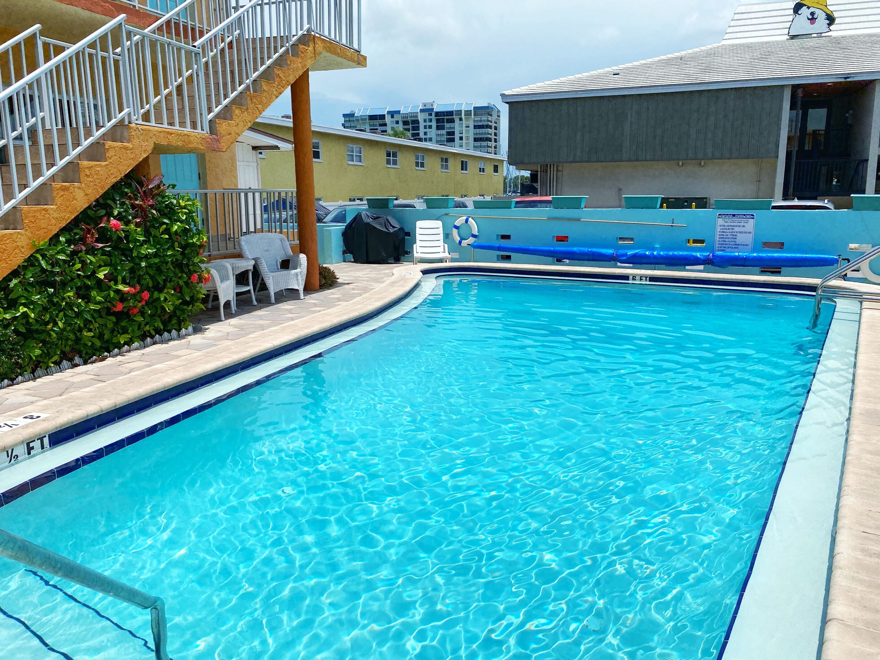 A swimming pool with a lifeguard stand, a covered area, and a staircase leading to an upper level.
