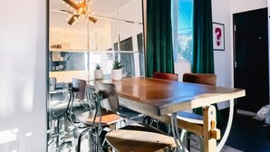 A modern meeting room with a glass partition, wooden table, leather chairs, and pendant lights.
