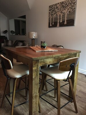 A dining area with a wooden table, four chairs, and a potted plant.