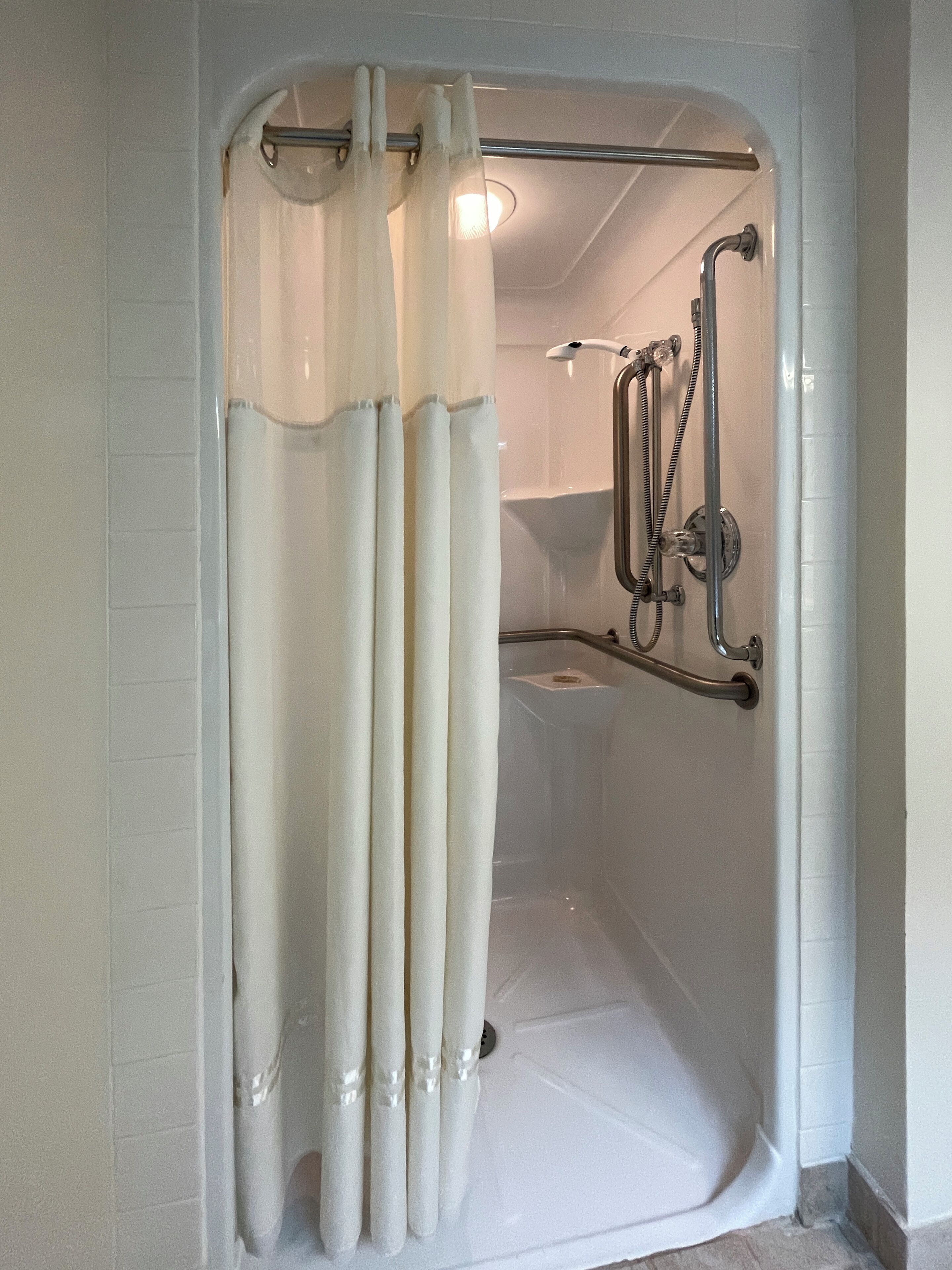 A glass-enclosed shower area with a handheld showerhead, a handheld showerhead, and a handheld showerhead.