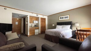 Una habitación de hotel con cama, sofá, escritorio, microondas y kitchenette.