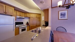 Una cocina con armarios de madera, un lavamanos de acero inoxidable y una mesa de comedor con sillas.