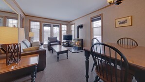 Una sala de estar con sofá, mesa de centro, televisor, chimenea y mesa de comedor con sillas.