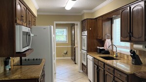 Una cocina con armarios de madera, refrigerador, microondas, horno y lavavajillas.
