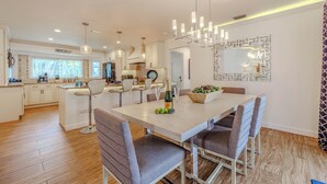 A modern kitchen with white cabinets, a central island, and pendant lighting. - Sleeps 6 - 3BR - 2BA - pool - Sun deck - Coastal (Cape Coral)