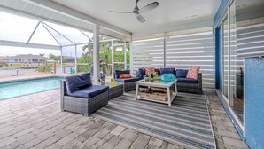 A covered outdoor area with a pool, wicker furniture, and a ceiling fan. - Sleeps 6 - 3BR - 2BA - pool - Sun deck - Coastal (Cape Coral)