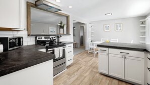 A modern kitchen with white cabinetry, a black countertop, and a stainless steel stove. - Poolside Paradise with Hot Tub (Boise)