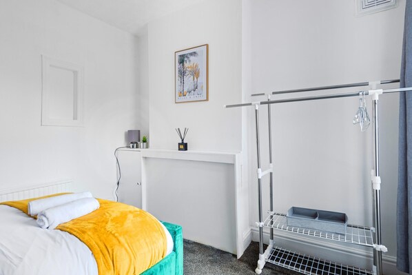 A hotel room with a bed, a desk, a radiator, and a window.