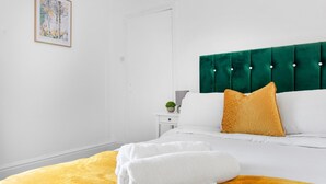 A hotel room with a bed, a nightstand, a green headboard, and a yellow throw blanket. - Leicester/1bedapart/petsok/tv/wifi/restaurantsnear (Leicester)