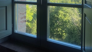 A room with a large window overlooking a forested landscape. - Villa Angela Ranza 55 (città di castello)