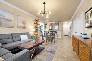 A modern living room with a grey sofa, a wooden coffee table, and a dining area with a table and chairs. - Spacious 4 Bedroom Condo Resort Close to Disney (Davenport)