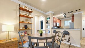 A modern kitchen with wooden shelves, a dining table with chairs, and a bar area. - Spacious 4 Bedroom Condo Resort Close to Disney (Davenport)