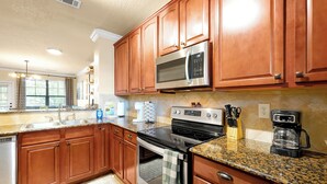 A kitchen with wooden cabinets, stainless steel appliances, granite countertops, and a built-in oven. - Spacious 4 Bedroom Condo Resort Close to Disney (Davenport)