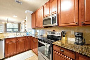 A kitchen with wooden cabinets, stainless steel appliances, granite countertops, and a built-in oven. - Spacious 4 Bedroom Condo Resort Close to Disney (Davenport)