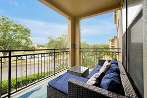 A balcony with wicker furniture and a view of a road and buildings. - Spacious 4 Bedroom Condo Resort Close to Disney (Davenport)