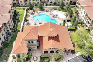 A hotel with a red-tiled roof, a swimming pool, and a landscaped courtyard. - Spacious 4 Bedroom Condo Resort Close to Disney (Davenport)