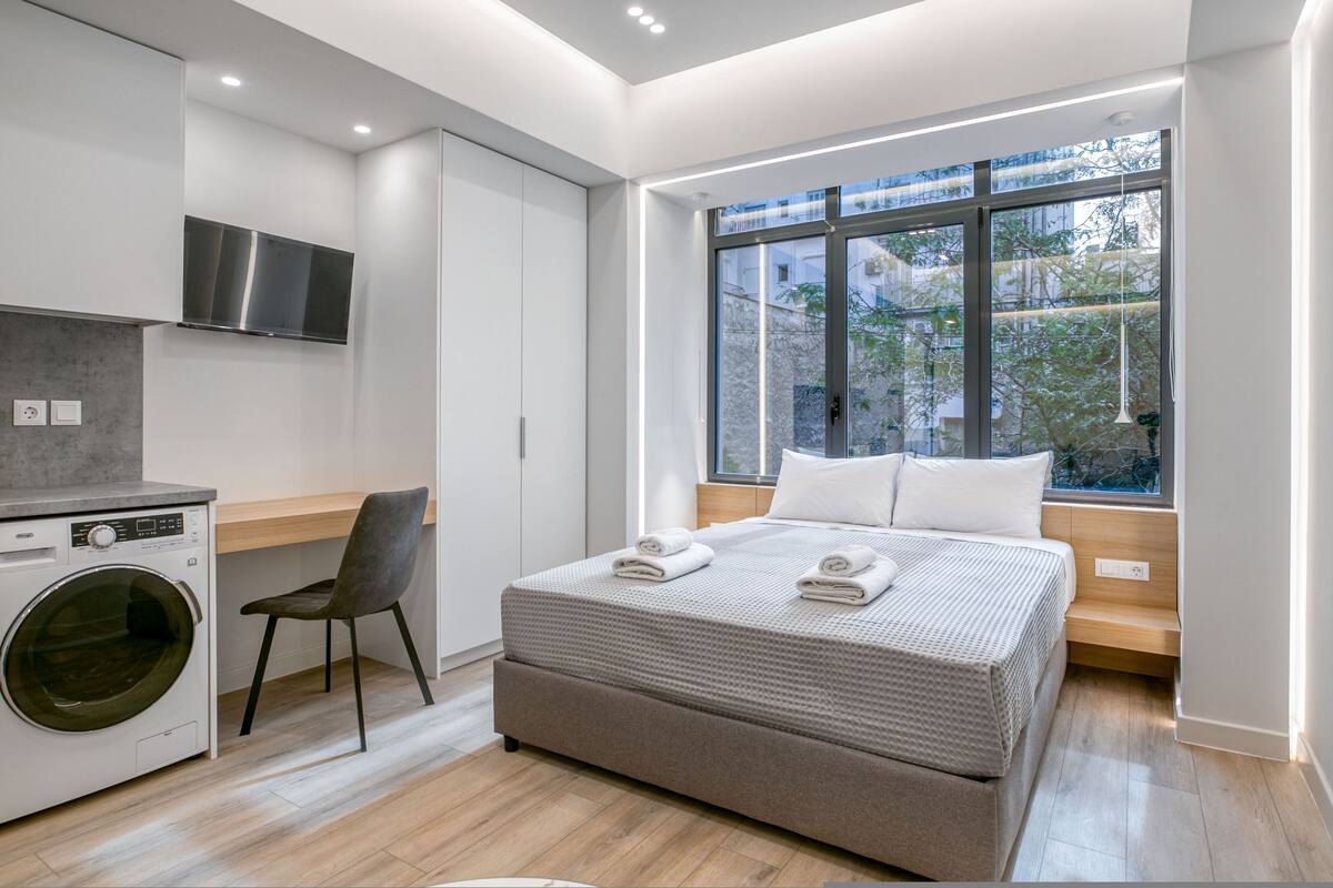 Une chambre moderne avec un grand lit, un lave-linge et un espace bureau.