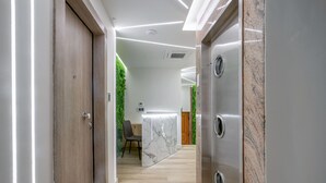 A hallway with a wooden door, a marble reception desk, and a green wall. - Porto Pireo by Superhost365 (Piraeus)