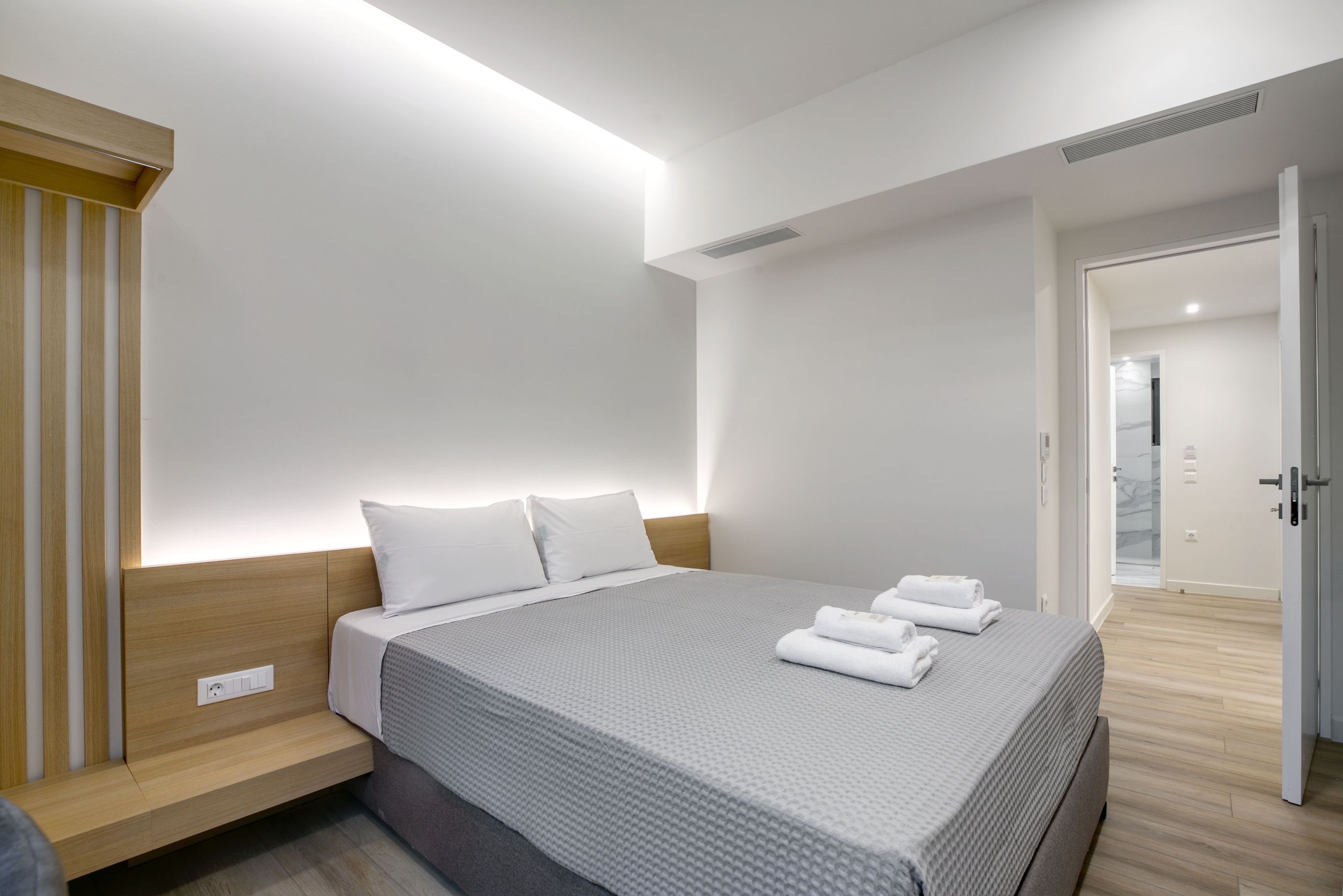 A modern hotel room with a neatly made bed, a bedside table, and a built-in bench.