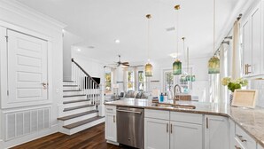 Una cocina moderna con armarios blancos, electrodomésticos de acero inoxidable y una escalera de madera.