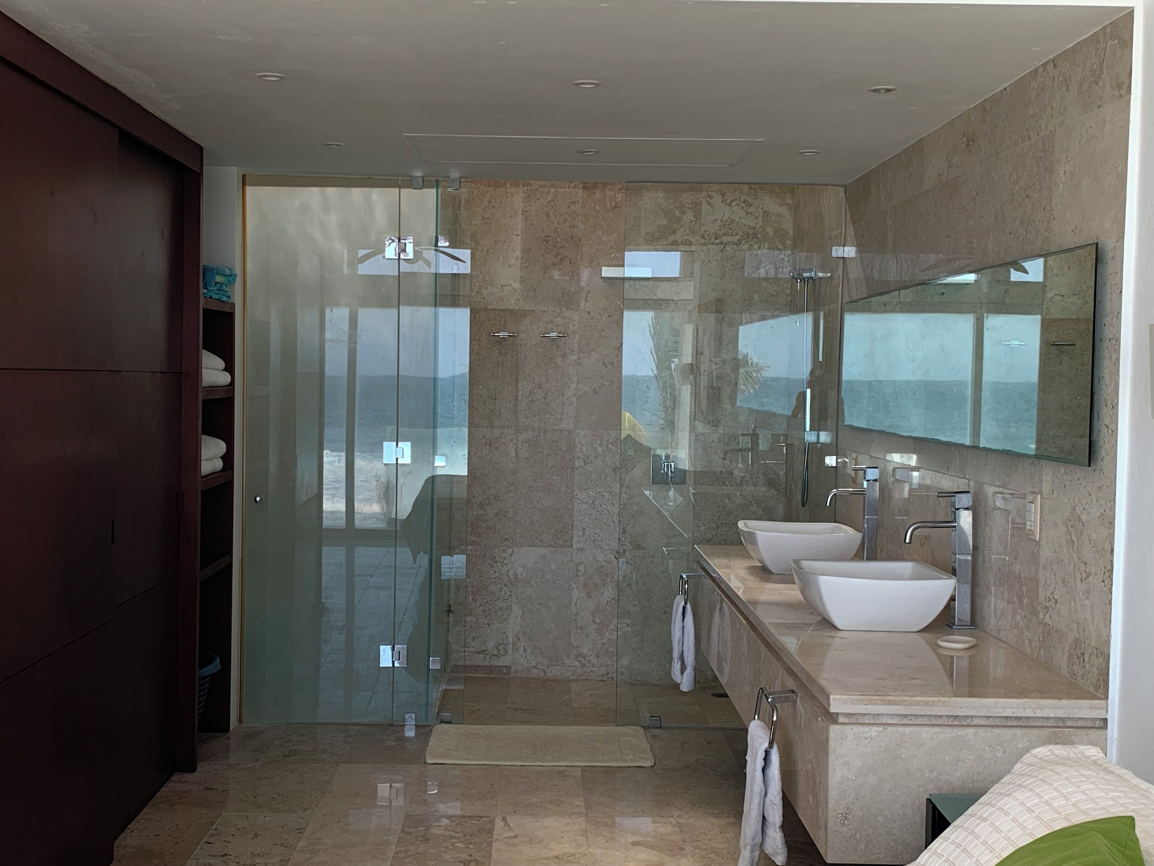 A modern bathroom with a glass shower enclosure, two sinks, and a large mirror.