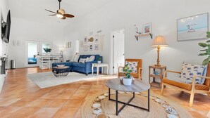A spacious living room with a blue sofa, a round coffee table, and a ceiling fan. - Casita near Madeira Beach (St. Petersburg)