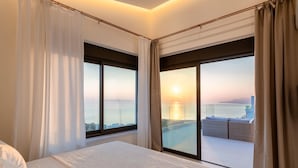 A hotel room with a large bed, a view of the cityscape, and a balcony with outdoor seating. - Luxury Villa Verde (Malevizi)