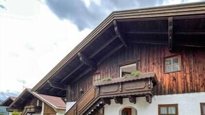 A traditional wooden chalet with a steeply pitched roof, a balcony with plants, and a white facade.