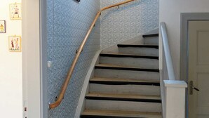Una escalera con barandilla de madera y un papel tapiz decorado.