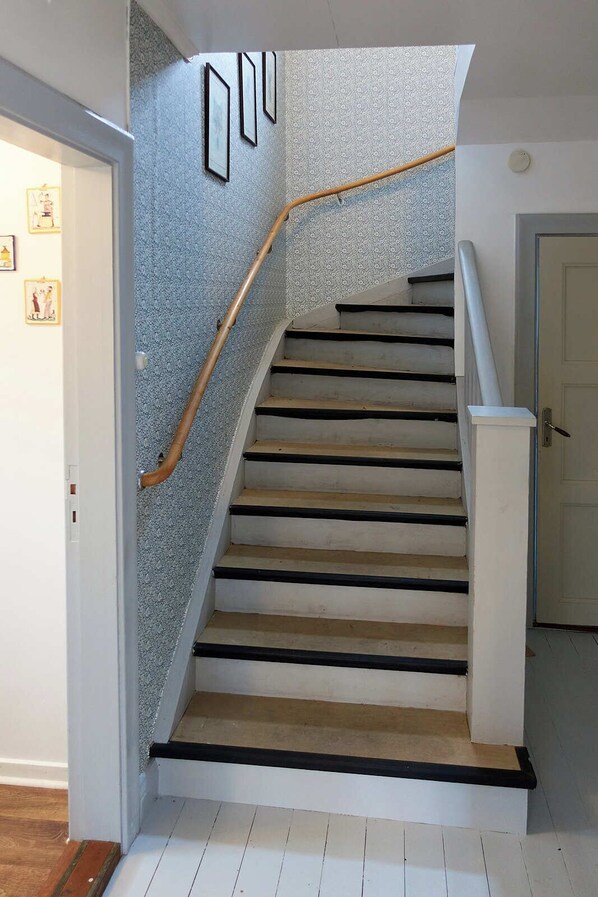 Un escalier avec une rampe en bois et un mur orné de motifs.