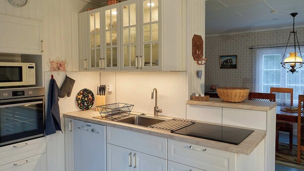 Una cocina moderna con armarios blancos, horno empotrado, microondas y un lavabo con escurreplatos.