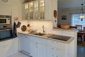 Una cocina moderna con armarios blancos, horno empotrado, microondas y un lavabo con escurreplatos.
