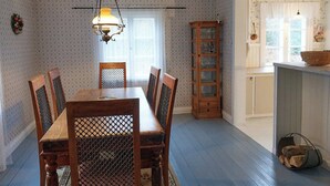 Comedor con mesa y sillas de madera, papel tapiz estampado, candelabro y aparador.