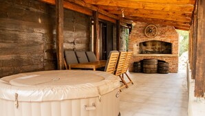 Un espace extérieur accueillant avec un coin salon, un jacuzzi, des meubles en bois et une cheminée en briques.