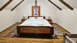 Une chambre avec un lit en bois, deux tables de chevet, une fenêtre avec des rideaux à carreaux et un plancher en bois.