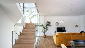 Una sala de estar moderna con una escalera, un sofá amarillo y un televisor.