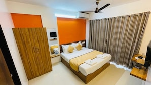 A modern hotel room with a large bed, a wooden wardrobe, a bedside table with a lamp, and a ceiling fan. - Hotel Habitat Inn - Pune (Pune)