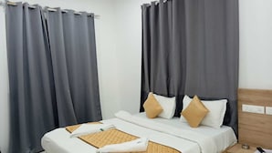 A hotel room with a bed, curtains, a bedside table, and a nightstand. - Hotel Habitat Inn - Pune (Pune)