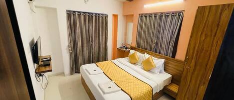 A hotel room with a bed, a ceiling fan, a TV, and curtains.