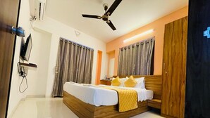 A modern bedroom with a wooden bed, a ceiling fan, and a wardrobe. - Hotel Habitat Inn - Pune (Pune)