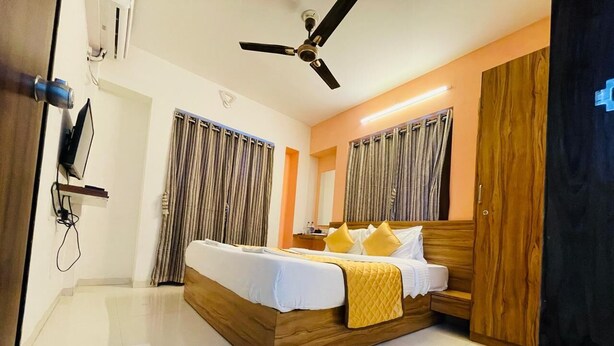 A modern bedroom with a wooden bed, a ceiling fan, and a wardrobe. - Hotel Habitat Inn - Pune (Pune)